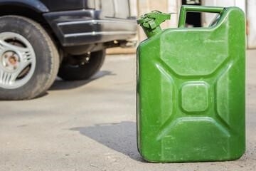 Green jerry can close-up on blurred background of black car